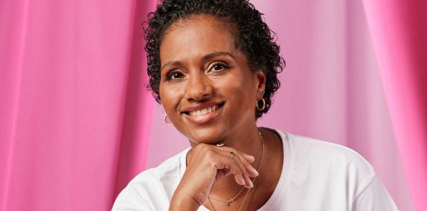 Vrouw met donkere krullen kijkt lachend in de camera