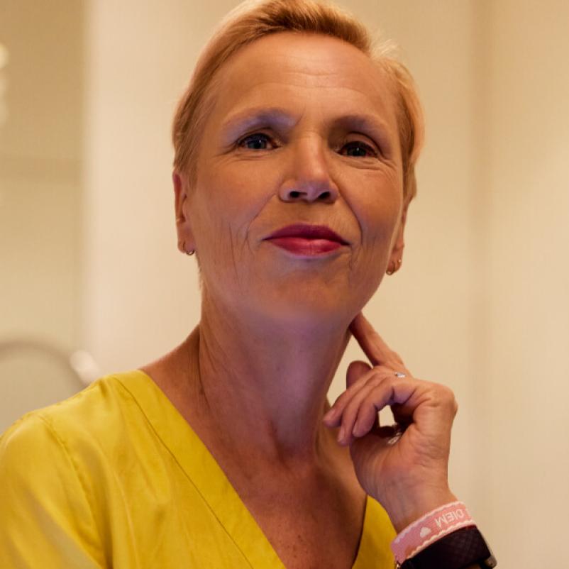 Vrouw in gele jurk kijkt in camera