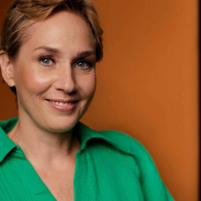 Vrouw in groene blouse kijkt in de camera