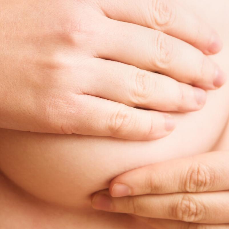 Hand gaat over borst voor borstonderzoek