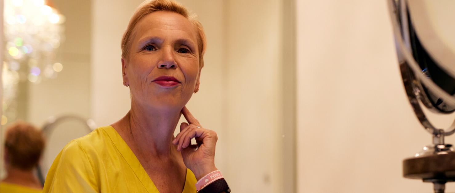 Vrouw in gele jurk kijkt in camera