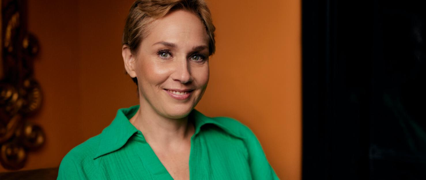 Vrouw in groene blouse kijkt in de camera